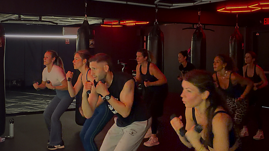 Large group squatting with light weights during OG Kickboxing Burn